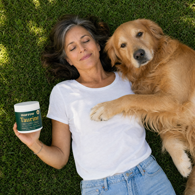 Dog mom relaxing on the grass with her senior golden retriever and Marrow Taurine