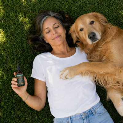 Dog mom relaxing on the grass with her senior golden retriever and Marrow Taurine